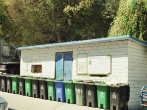 A row of green and blue trash cans next to a building